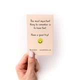Travel Packing Checklist Zine shown in hand, featuring a peachy-pink cover with black text reading "The most important thing to remember is to have fun!" and "Have a good trip!" with a yellow smiley face sticker and Kwohtations branding