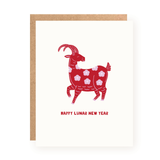 Greeting card featuring a stylized red goat decorated with pink flowers and the phrase "Happy Lunar New Year" on a white background with a kraft paper envelope behind.