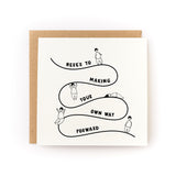 Encouragement card with playful line art showing figures navigating a winding path with inspiring message about moving forward.