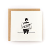 Square white greeting card featuring a simple black line illustration of a person holding a sign with the handwritten message "You are doing a great job being a person in this world," paired with a brown kraft envelope.