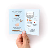Open mini zine "Things to Do When You're in a Depressive Spiral" showing illustrated pages with self-care suggestions like cleaning, organizing closets, and spending time with friends. Hand holding small blue booklet with simple line drawings and encouraging text in black print.