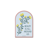 Beauty is All Around Us Sticker featuring an arch-shaped design with yellow flowers and green leaves on a soft blue background with rose gold border. Text reads "Beauty is All Around Us" in a handwritten style.