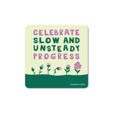 Sticker with the phrase celebrate slow and unsteady progress above a row of blooming flowers on a green background