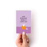 Hand holding a mini zine titled What Resilience Actually Looks Like with a minimalist purple design