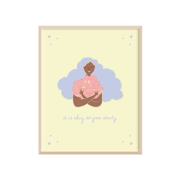 8 x 10 positive affirmations art print with the gentle reminder "It's Okay to Grow Slowly" handwritten underneath hand drawn illustration a woman with curly hair hugging a giant pink rose. The artwork is printed on a light yellow background with blue, pink, and brown illustrations.