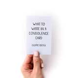 Hand holding small purple booklet, which is a how to guide on what to write in a sympathy card, titled "What to write in a condolence card (some ideas)"