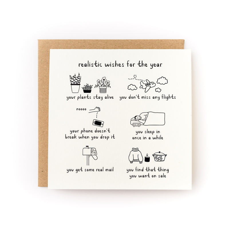 Realistic Wishes for the Year Letterpress Card featuring hand-drawn illustrations of everyday hopes: thriving plants, catching flights, unbroken phone, peaceful sleep, receiving mail, and finding sale items. White square card with black ink sketches paired with kraft envelope.