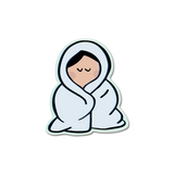 Cozy Sticker featuring a minimalist illustration of a figure wrapped snugly in a light blue blanket, eyes peacefully closed, drawn in a cute cartoon style with mint green border. Die-cut vinyl design perfect for laptops and water bottles.