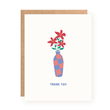 Thank you card featuring a simple illustration of a blue and pink checkered vase holding three red flowers with green leaves, set on a white background with a brown kraft envelope behind.