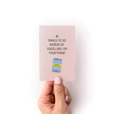 Hand holding the "30 Things to Do Instead of Looking at Your Phone Zine" with a phone illustration on the cover.