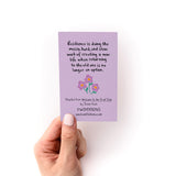 Hand holding a purple card with a quote about resilience and an illustration of three pink flowers.