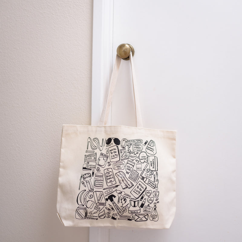 What We Carry cotton tote bag hanging on doorknob