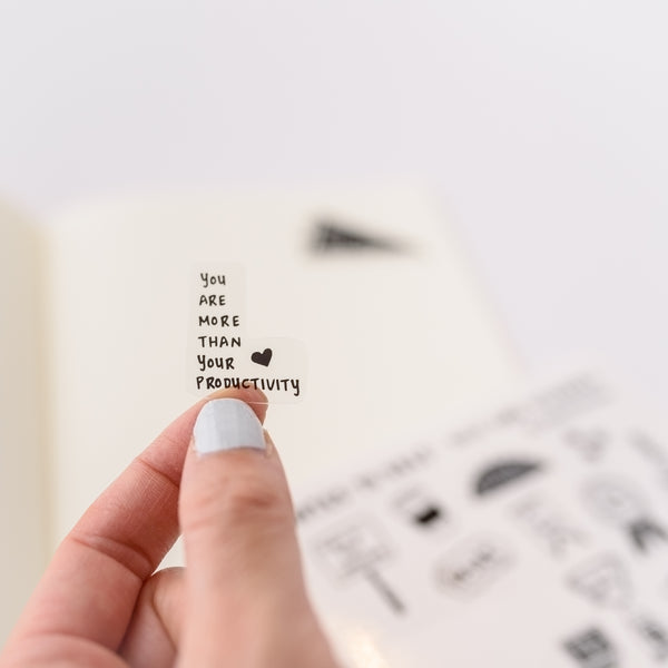 Hand holding cute positive self care transparent journal sticker that says You Are More Than Your Productivity