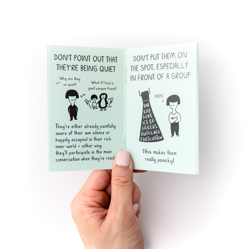 Hand holding small open mint book with illustrations of a person and says "Don't point out that they're being quiet. Don't put them on the spot, especially in front of a group"
